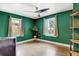 Spacious bedroom with green walls, two windows providing natural light, hardwood floors, and a ceiling fan at 4509 Eliot St, Denver, CO 80211