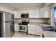 Kitchen area features stainless steel appliances, white cabinets, and a window view at 7877 York St # 1, Denver, CO 80229