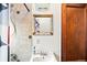 Small bathroom showcasing neutral tile shower and white sink with rustic framed mirror and door at 3737 Jason St, Denver, CO 80211