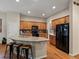 Spacious kitchen with granite countertops, black appliances, wood floors, and three-seat island at 5377 Cloverbrook Cir, Highlands Ranch, CO 80130