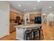 Open kitchen with granite island, wood floors, wood cabinets, and black appliances at 5377 Cloverbrook Cir, Highlands Ranch, CO 80130