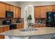 Modern kitchen with wood cabinets, granite counters, stainless steel sink, and black appliances at 5377 Cloverbrook Cir, Highlands Ranch, CO 80130