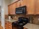 Kitchen with granite countertops, wooden cabinetry, black appliances, and tiled backsplash at 5377 Cloverbrook Cir, Highlands Ranch, CO 80130