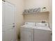 Well-lit laundry room equipped with washer, dryer, storage shelf, and door to outside at 5377 Cloverbrook Cir, Highlands Ranch, CO 80130