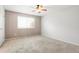 Empty bedroom featuring neutral carpet, ceiling fan, and a large window at 3855 S Monaco St # 166, Denver, CO 80237