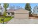 Home exterior featuring stone accents, a two-car garage, and a well-maintained lawn with a mailbox and trees at 9960 Garland Ln, Broomfield, CO 80021