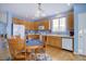 Eat-in kitchen features wooden cabinetry, white appliances, and a dining table with seating for four near a sunny window at 4211 Miners Candle Pl, Castle Rock, CO 80109