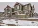 View of townhome exterior with a green facade and stone accents, surrounded by snow-covered landscaping at 23545 E Platte Dr # C, Aurora, CO 80016