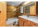 Well-lit bathroom features a shower-tub combo, a sink with storage underneath, and natural wood finishes at 10436 Jeanette Ct, Morrison, CO 80465