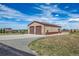 Spacious metal building with large garage doors and stone accents on a sunny day with a home in the background at 11624 Dunrich Rd, Parker, CO 80138