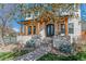 Inviting two-story home featuring stone accents, a covered porch, and landscaped front yard with mature trees at 2600 S Adams St, Denver, CO 80210