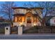 Elegant two-story home boasts stone accents, a covered front porch with wooden columns, and a beautifully landscaped yard with iron fence at 2600 S Adams St, Denver, CO 80210
