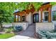 Charming two-story home with stone accents, mature trees, landscaped yard, and walkway to porch at 2600 S Adams St, Denver, CO 80210