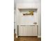Hallway with wood floors, white accent walls, and a built-in cabinet with white hexagon tiling at 2 N Adams St # 108, Denver, CO 80206
