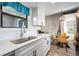 Modern kitchen with white cabinetry, stainless steel sink, quartz counters, stylish backsplash, and adjacent dining area at 8378 S Upham Way # B305, Littleton, CO 80128