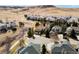 An elevated shot of the property, surrounded by mature trees, other houses, and rolling, grassy hills at 7858 Oban Ct, Lone Tree, CO 80124