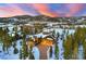 Stunning aerial view of a luxury mountain home with a long driveway nestled in a snow-covered forest at sunset at 219 Glen Eagle Loop, Breckenridge, CO 80424