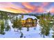 A grand, snow-laden residence amidst a snowy landscape showcases majestic mountain views and tree-lined surroundings at 219 Glen Eagle Loop, Breckenridge, CO 80424