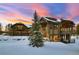 A luxurious mountain home featuring natural wood siding, stone accents, and a three car garage at sunset at 219 Glen Eagle Loop, Breckenridge, CO 80424