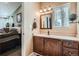 Bathroom with wooden cabinets, a mirror, vanity lighting and a view of the bedroom at 13495 Shiloh Rd, Conifer, CO 80433