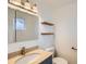 Bathroom featuring a stylish vanity with marble countertop and modern fixtures, complemented by natural wood shelves at 5669 Johnson Ct, Arvada, CO 80002