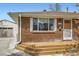 Close-up of brick house with a wooden porch, showcasing the front entrance and garage at 5669 Johnson Ct, Arvada, CO 80002