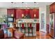 Eat in kitchen with red cabinets, decorative backsplash, and seating for three at island at 4236 Frederick Cir, Longmont, CO 80503