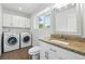 Well-lit bathroom includes a washer and dryer, granite countertop, and natural light from the window at 1203 S Zeno Way # B, Aurora, CO 80017
