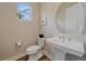 Stylish half-bathroom features a pedestal sink, round mirror, and hardwood floors at 5189 Vivian St, Wheat Ridge, CO 80033