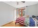 Another angle of the bright bedroom with hardwood floors and the bed with a colorful blanket at 11970 W Pleasant Ave, Lakewood, CO 80401