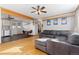 Open-concept living room and dining area with hardwood floors, a gray sectional couch, and natural light at 11970 W Pleasant Ave, Lakewood, CO 80401