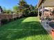 Spacious backyard featuring a lush lawn, a wooden fence, and patio furniture at 3842 S Quebec St, Denver, CO 80237