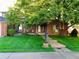 Charming brick home with a covered porch, lush lawn, and mature trees at 3842 S Quebec St, Denver, CO 80237