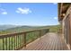 Outdoor wooden deck with dark wood railing features an amazing mountain range view under a blue cloudy sky at 25704 Shiloh, Conifer, CO 80433