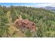 Aerial view featuring a charming log cabin with a rustic roof, surrounded by a dense forest at 25704 Shiloh, Conifer, CO 80433