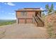 An exterior image of a log cabin featuring a garage and staircase at 25704 Shiloh, Conifer, CO 80433