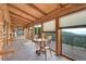 Enclosed sunroom with tile flooring, wooden furniture, and expansive windows showcasing the natural scenery at 25704 Shiloh, Conifer, CO 80433