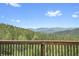 A stunning mountain view from deck with wooden railing showing lush green trees under a blue sky at 25704 Shiloh, Conifer, CO 80433