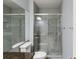 Bathroom featuring a glass-enclosed shower with tile accents, a toilet, and a large mirror reflecting the space at 8105 E Bayaud Ave, Denver, CO 80230