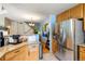 Modern kitchen with stainless steel appliances, wooden cabinets, and a view of staircase and living space at 8105 E Bayaud Ave, Denver, CO 80230