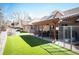 Beautiful backyard featuring a covered patio with outdoor seating and lush green artificial turf creating a serene outdoor space at 7931 W Paine Ave, Lakewood, CO 80235