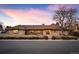 A brick home with a brown tile roof is enhanced by a manicured front yard at dusk at 7931 W Paine Ave, Lakewood, CO 80235