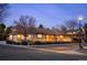 Warm home with brick facade, brown tile roof, illuminated landscape, and mature trees at 7931 W Paine Ave, Lakewood, CO 80235