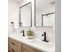 Bathroom featuring double sinks with modern black fixtures and marble countertop at 3540 Everett St, Wheat Ridge, CO 80033