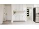 Hallway with modern white cabinets, stainless steel appliances, and light gray wood flooring at 3540 Everett St, Wheat Ridge, CO 80033