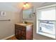 Well-lit bathroom featuring a vanity with granite countertop, decorative mirror, and a window at 1322 Kalamath St, Denver, CO 80204