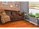 Bright bedroom featuring a brick accent wall, a plush sofa, and natural light streaming through the window at 1322 N Kalamath St, Denver, CO 80204