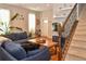 Bright living room with hardwood floors, a cozy sofa, and a staircase featuring dark iron railings at 1322 Kalamath St, Denver, CO 80204