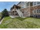Backyard view with a stone facade, covered patio, stairs to the upper deck, and a manicured lawn at 5010 Persimmon Ln, Castle Rock, CO 80109