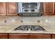 Close-up of a gas stovetop with granite countertops and tiled backsplash with a stainless microwave oven above at 5010 Persimmon Ln, Castle Rock, CO 80109